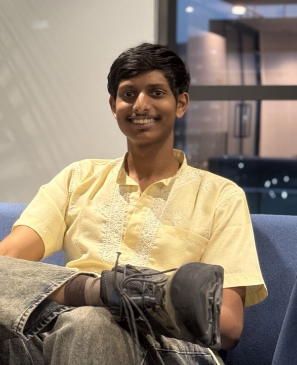 Sreeram, smiling, sitting on a blue sofa