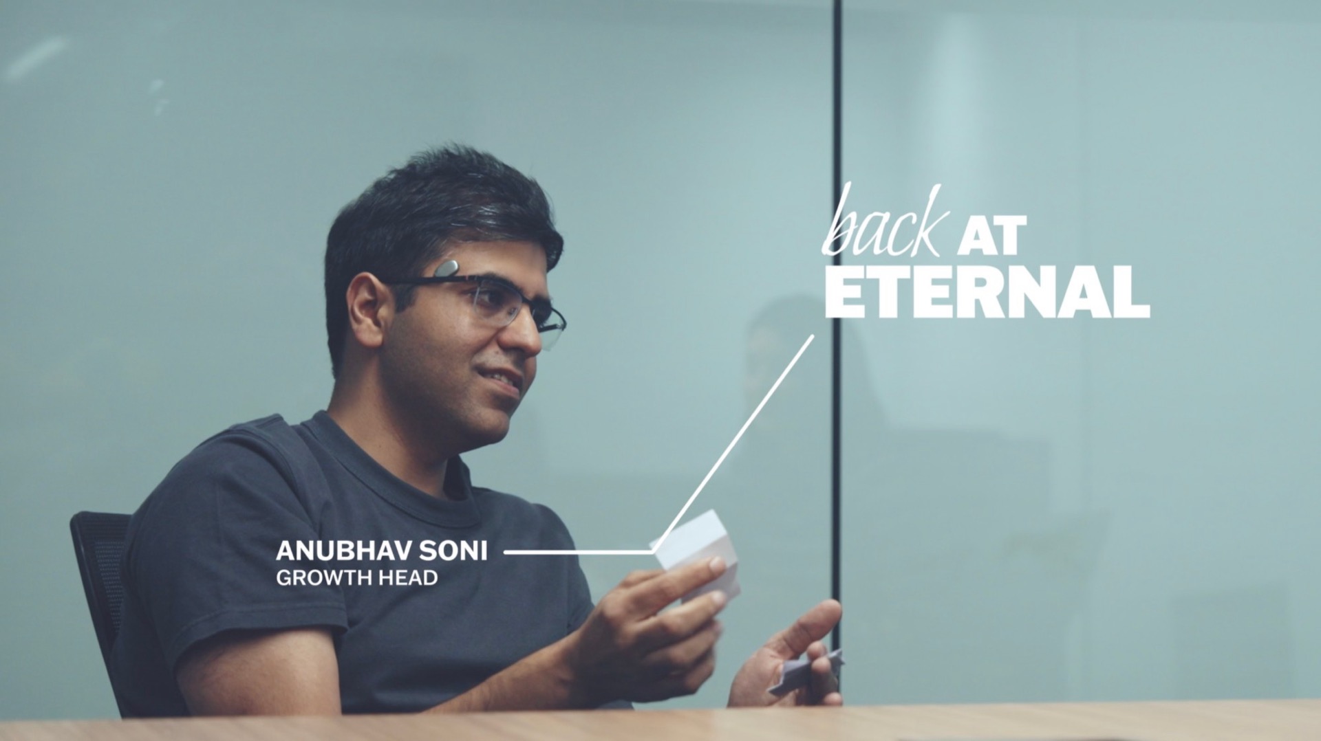 Anubhav Soni in a glass-walled meeting room, holding a paper chit