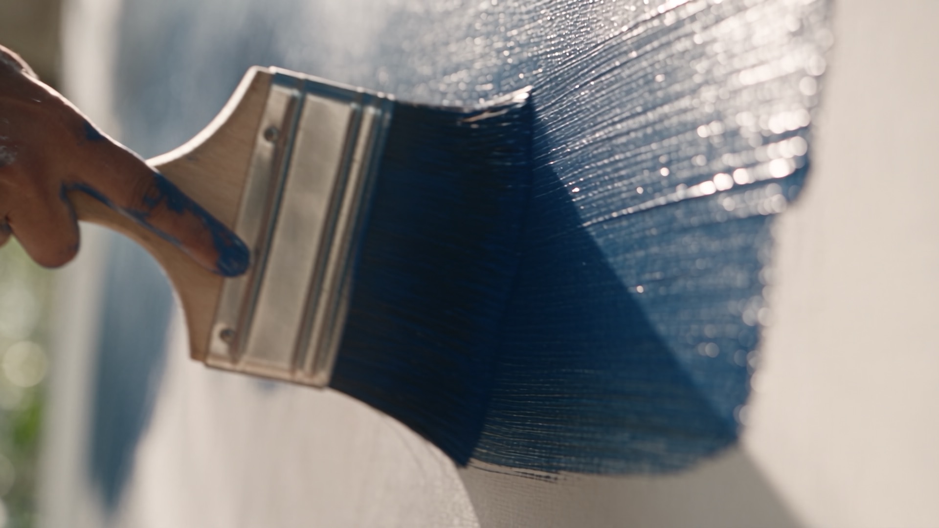 A brush drags blue paint across the canvas