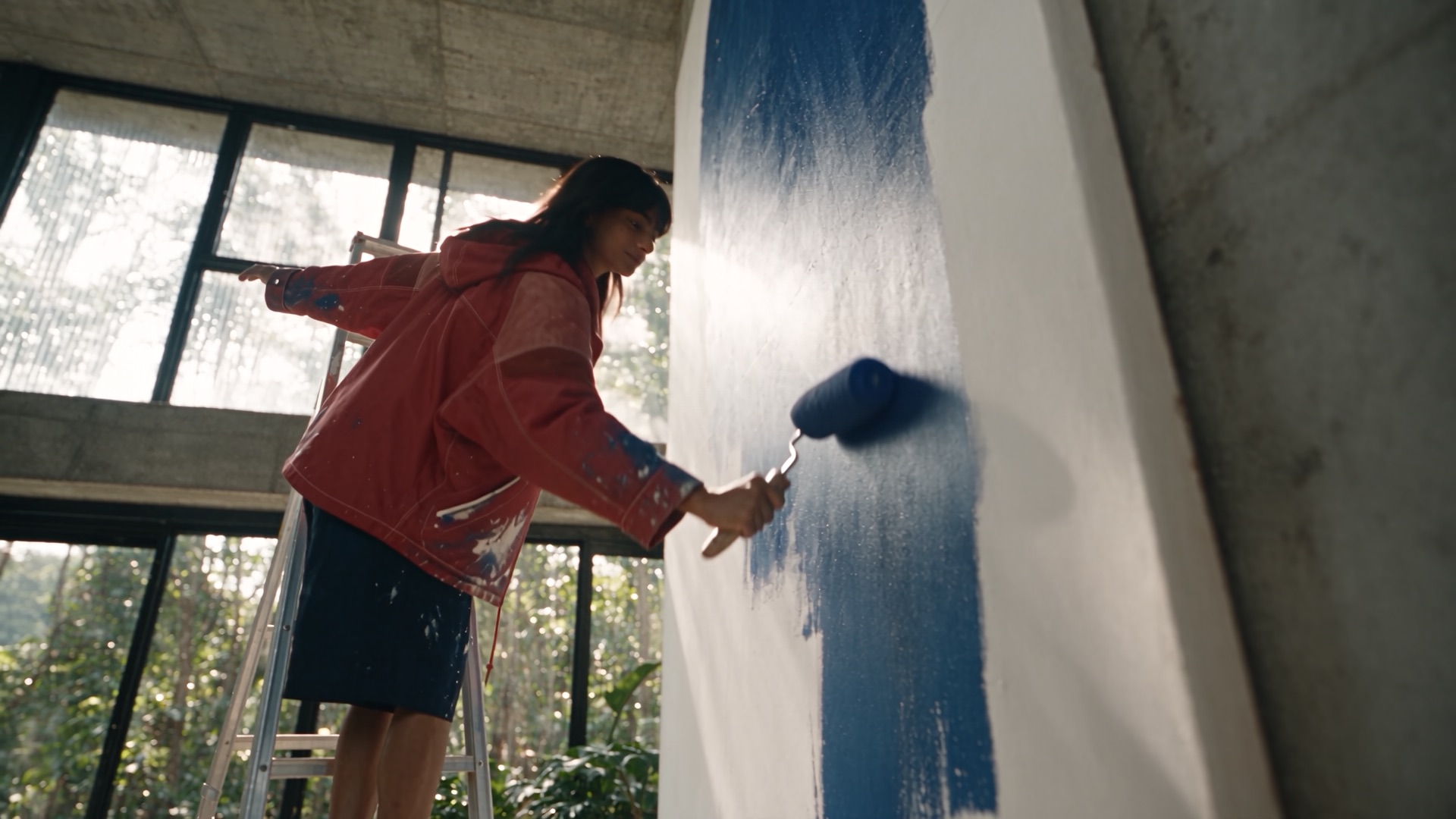 She rolls blue paint up the canvas