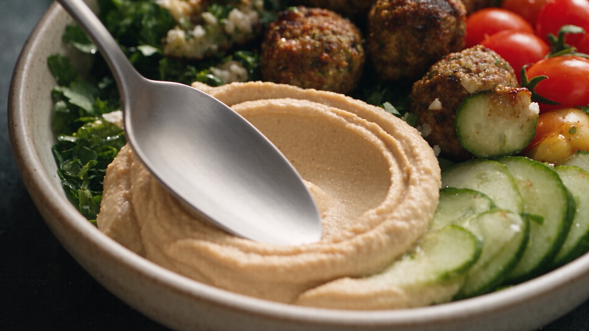 A spoon swirls through hummus