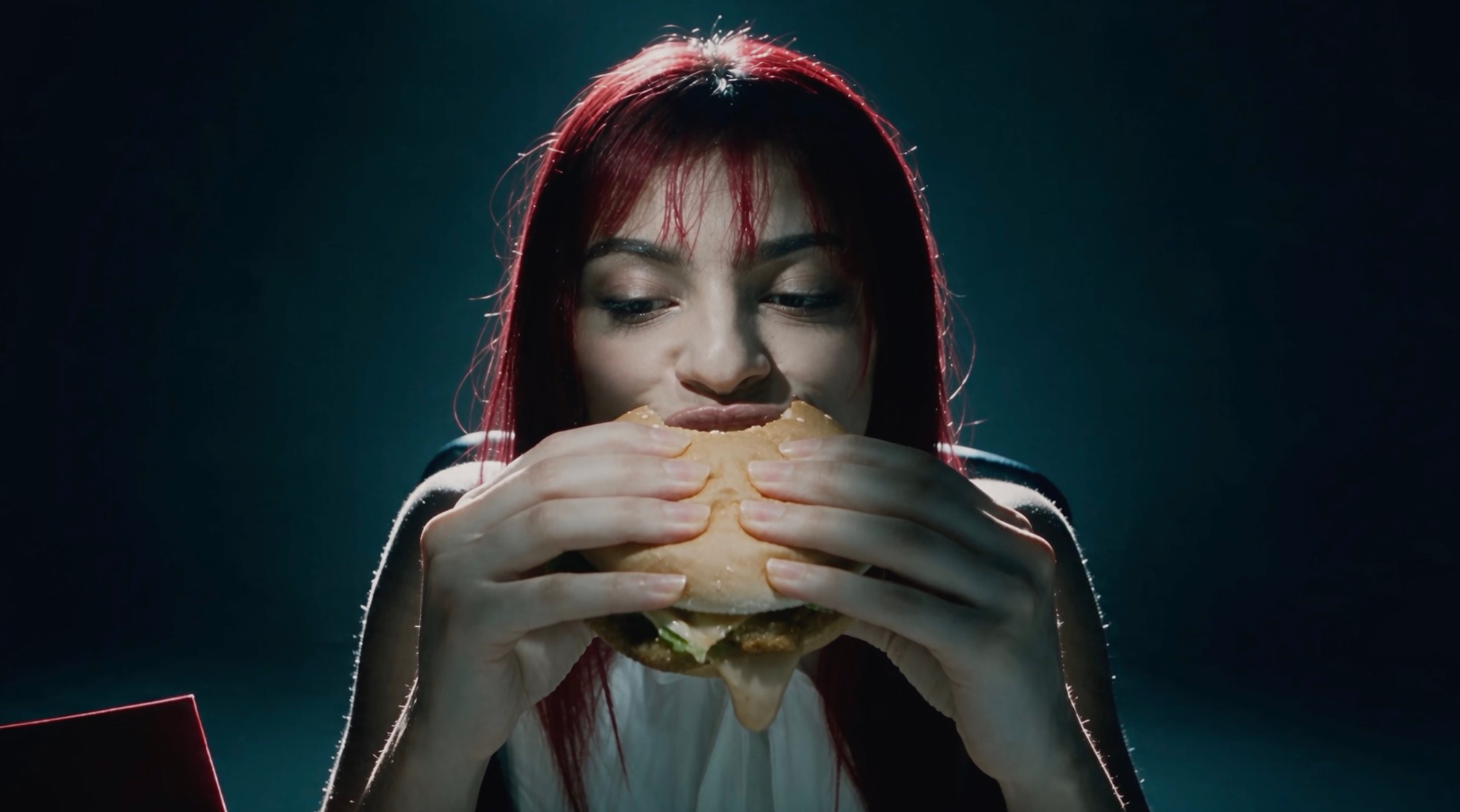Her first bite, in the petrol-blue dark