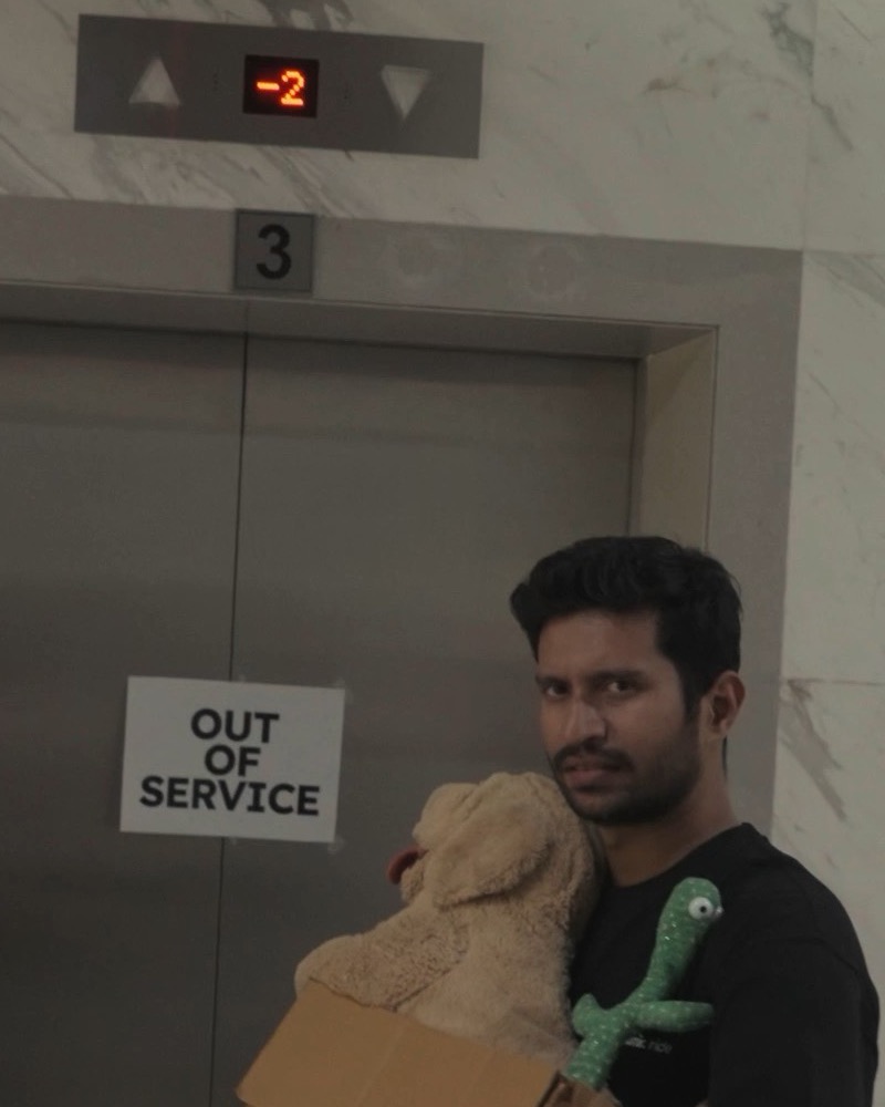 Rohan, deadpan, holds the box at the lift, under an out of service sign