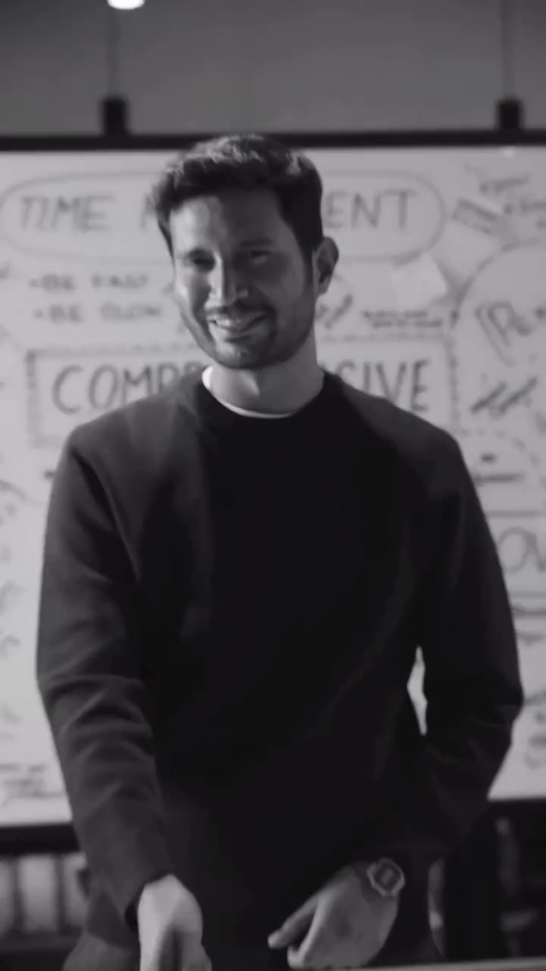 A speaker smiles in front of the whiteboard