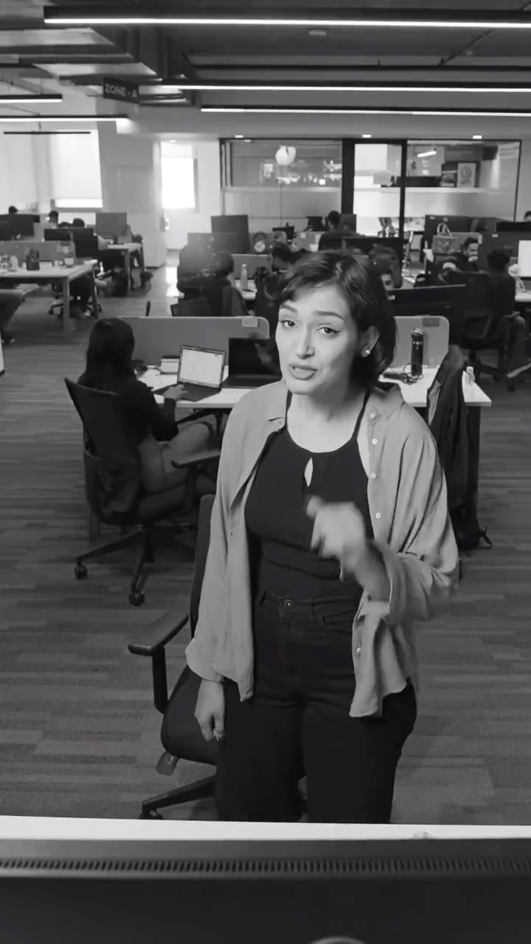 A speaker talks to camera across the open office floor