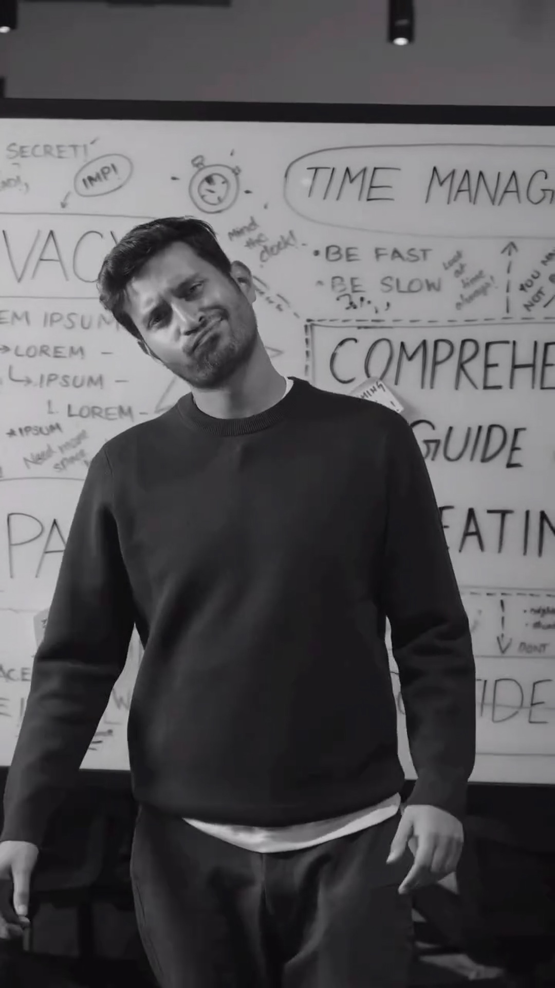 A speaker shrugs in front of the whiteboard